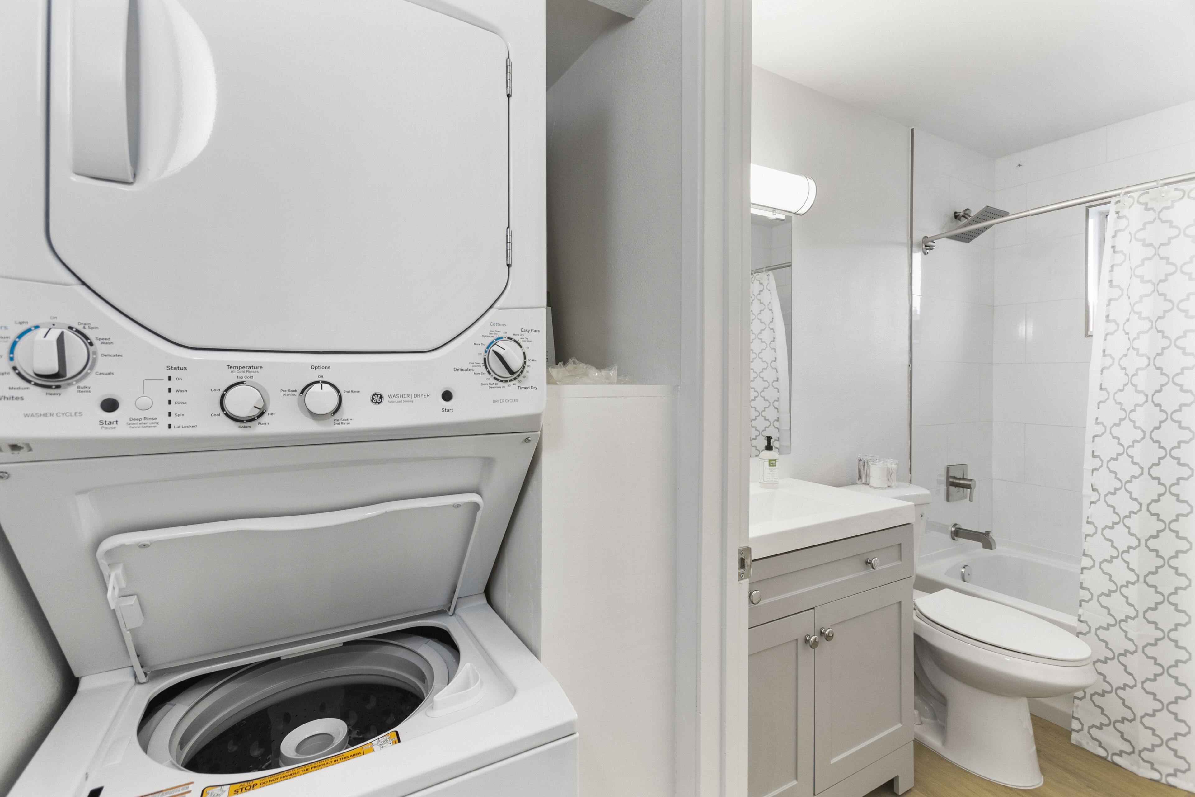 Un bagno moderno con lavatrice e asciugatrice integrate, un water e una cabina doccia.