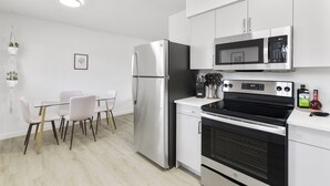 A modern kitchen with stainless steel appliances, a dining table with chairs, and a hanging plant. - Contemporary Condo in Central Biltmore (Phoenix)
