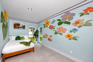 Een slaapkamer met een bed, een raam, een deur en een muur met bloemstickers.