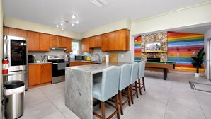 Una cocina moderna con armarios de madera, un refrigerador de acero inoxidable y una isla integrada con taburetes de bar.