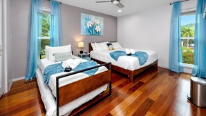 Habitación de hotel con dos camas, un ventilador de techo, un cuadro y vistas a zonas verdes.