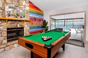 A pool table with balls, a stone fireplace, and a colorful wall. - Hibiscus16 Heated Pool/Beach/Pickleball/Tennis (Largo)