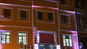 A multi-story building with a flat facade, multiple windows, and a visible entrance with a sign. - Derya Otel (Borcka)