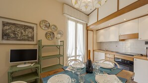 A dining area with a table set for four, a bottle of champagne, and a painting on the wall. - GuestHost - Comfortable two-room apartment perfect for 4 guests, it is ideal for a family or small groups of friends for a relaxing holiday. We are a few minutes walk from the sea, the city center and the train station. The accommodation is equipped with (Sanremo)