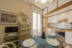 A dining area with a table set for four, a bottle of champagne, and a painting on the wall. - GuestHost - Comfortable two-room apartment perfect for 4 guests, it is ideal for a family or small groups of friends for a relaxing holiday. We are a few minutes walk from the sea, the city center and the train station. The accommodation is equipped with (Sanremo)