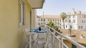 A balcony with a table set for two, a bottle of champagne, and a view of buildings. - GuestHost - Comfortable two-room apartment perfect for 4 guests, it is ideal for a family or small groups of friends for a relaxing holiday. We are a few minutes walk from the sea, the city center and the train station. The accommodation is equipped with (Sanremo)