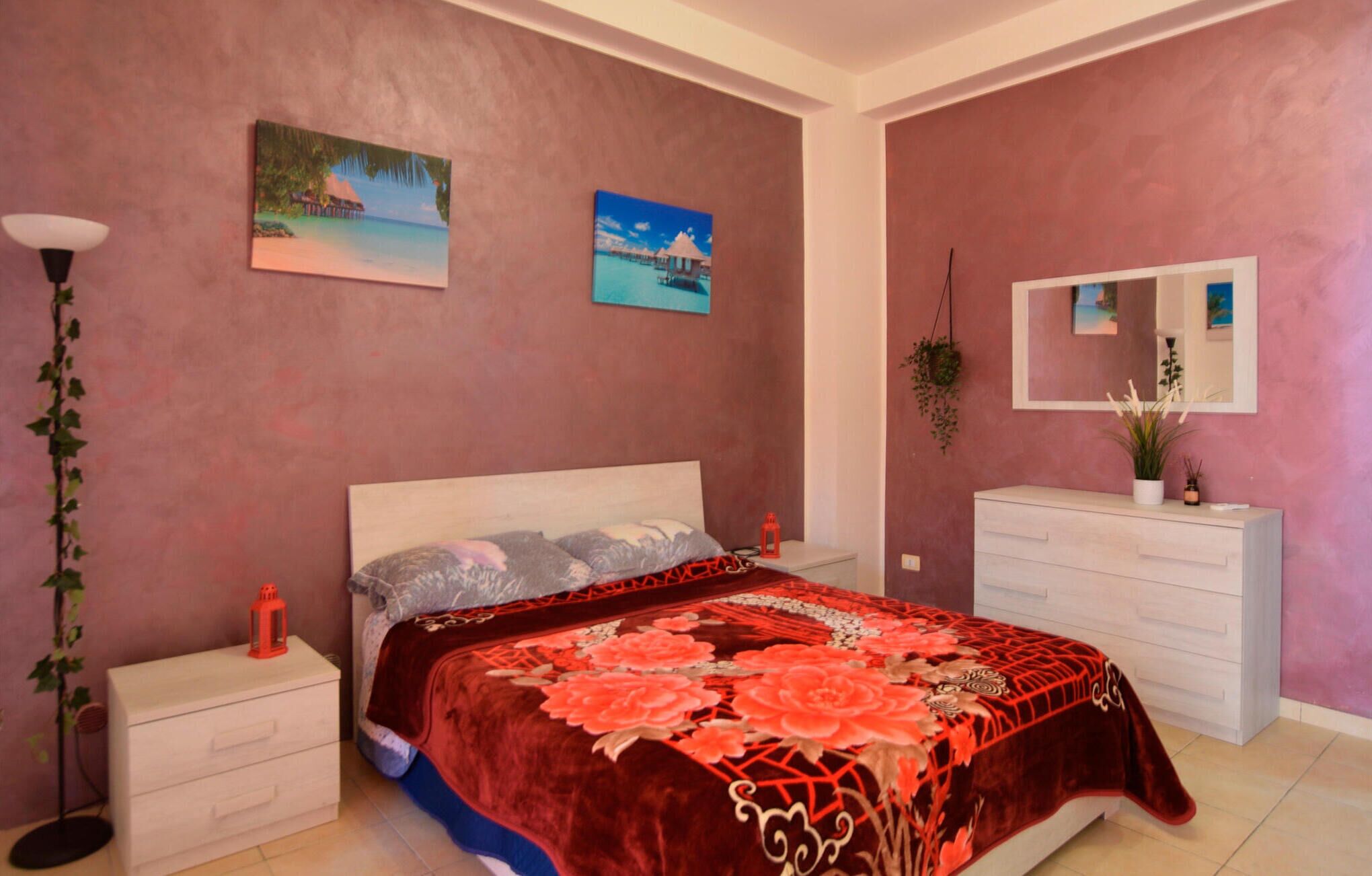 A bedroom with a bed, nightstands, a dresser, a mirror, and wall art.