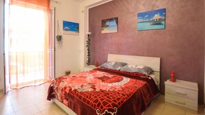 Una camera da letto con un letto, un comodino, una lampada e una finestra con tende.