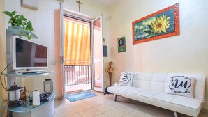 Un soggiorno con televisione, divano e un'opera d'arte appesa al muro.