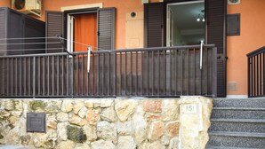 Un muro in pietra con una ringhiera in metallo, una porta con un oblò e il numero '151' sulla parete.