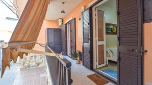 Un balcone con ringhiera in metallo, un muro in pietra e un pavimento piastrellato.