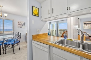 A kitchen with a wooden countertop, stainless steel sink, and white cabinets.