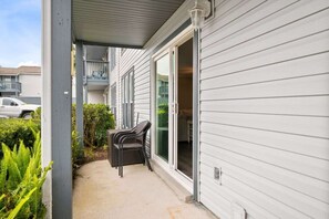 A covered outdoor area with a patio, a sliding glass door, and a car parked in the background.