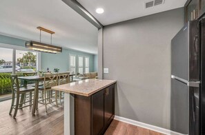 A modern kitchen with a built-in refrigerator, wooden cabinets, and a dining area with a table and chairs.