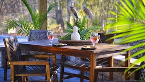 An outdoor wooden table set with two wine glasses, a decorative centerpiece, and two bird figurines. - Ultimate Space for Your Family! ~ TIEC ~ Fire Pit+ (Landrum)