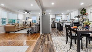 A spacious living area with a sofa and coffee table, a dining table with chairs, and a kitchen area with appliances and cabinets. - Ultimate Space for Your Family! ~ TIEC ~ Fire Pit+ (Landrum)