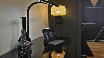 A modern lamp with a laptop on a stand, a decorative vase, and a geometric wall design.