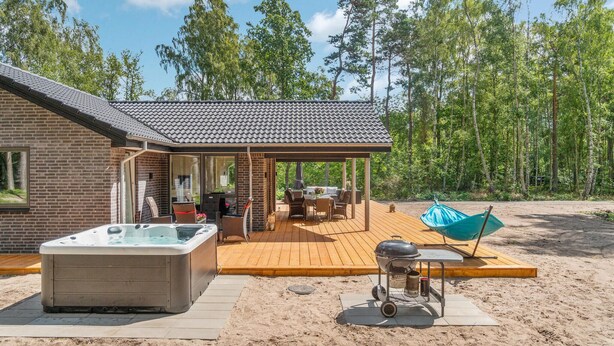 Une maison avec un patio, un jacuzzi et un barbecue.