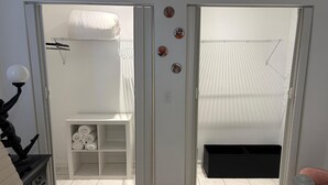 A hotel room with a bathroom, a white wardrobe, a black storage box, and a small shelf with towels. - New, Cozy & peaceful stay, 30 minutes from New Orleans. Family and pet friendly! (Slidell)