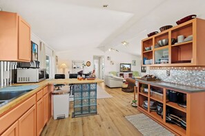 A spacious kitchen with wooden cabinets, a central island, and a dining area with a sofa.