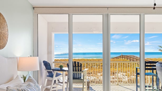 Une chambre dotée d’une grande porte-fenêtre coulissante donnant sur un balcon avec vue sur la plage.