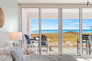 Un dormitorio con un amplio ventanal corredera que da a un balcón con vistas a la playa.