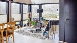 Una habitación acogedora con muebles de madera, un ventanal grande y una puerta negra.