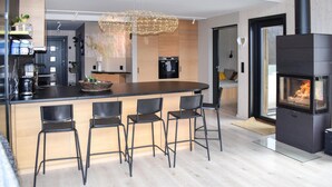 Una cocina moderna con una isla central, taburetes de bar, horno empotrado y chimenea.