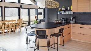 Una cocina moderna con una isla central, armarios de madera y encimera negra.