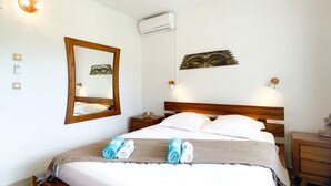 A neatly made bed with a wooden headboard, a wall-mounted air conditioner, and a mirror. - Zen Fairway Apartment Nestled in the heart of the golf course (Saint-François)