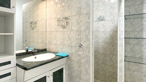 A bathroom with a sink, mirror, and shower area. - Zen Fairway Apartment Nestled in the heart of the golf course (Saint-François)