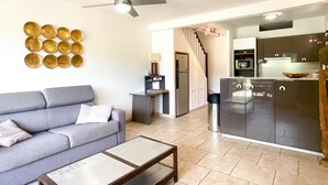 A living room with a grey sofa, a coffee table, and a ceiling fan. - Zen Fairway Apartment Nestled in the heart of the golf course (Saint-François)