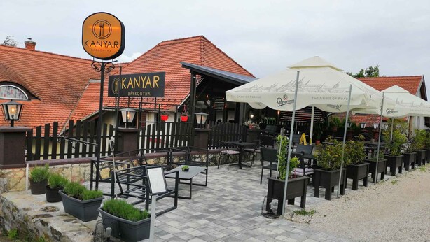 Een buitenruimte met tafels en stoelen, plantenpotten en parasols bij KANYAR BARKONYHA.