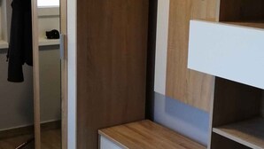 Een kamer met een kledingkast, een spiegel en een klein bureau met lades.
