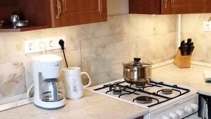 Een keuken met houten kastjes, een fornuis, een koffiezetapparaat en een magnetron.