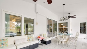 A spacious patio area with a dining table and chairs, a sofa with cushions, and a ceiling fan. - Pool, Grill & Golf Course Views: Spring Hill Stay! (Spring Hill)
