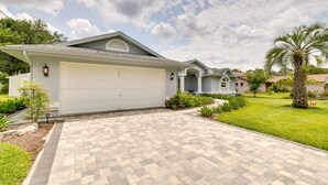 A residential house with a garage, a paved driveway, and a well-maintained lawn with a palm tree and a flamingo statue. - Pool, Grill & Golf Course Views: Spring Hill Stay! (Spring Hill)