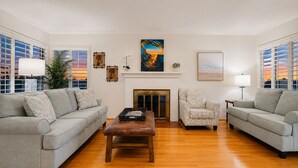 A living room with two sofas, a coffee table, a fireplace, and artwork on the walls.