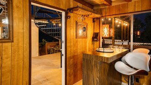 A wooden interior with a bar area, a staircase, and a view of the outside.