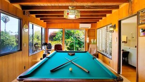 A pool table in a room with wooden walls and large windows.