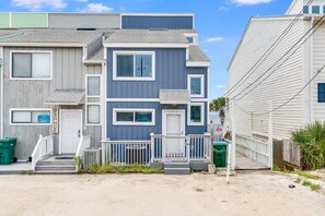 A multi-story residential building with a front porch and steps leading to the entrance.