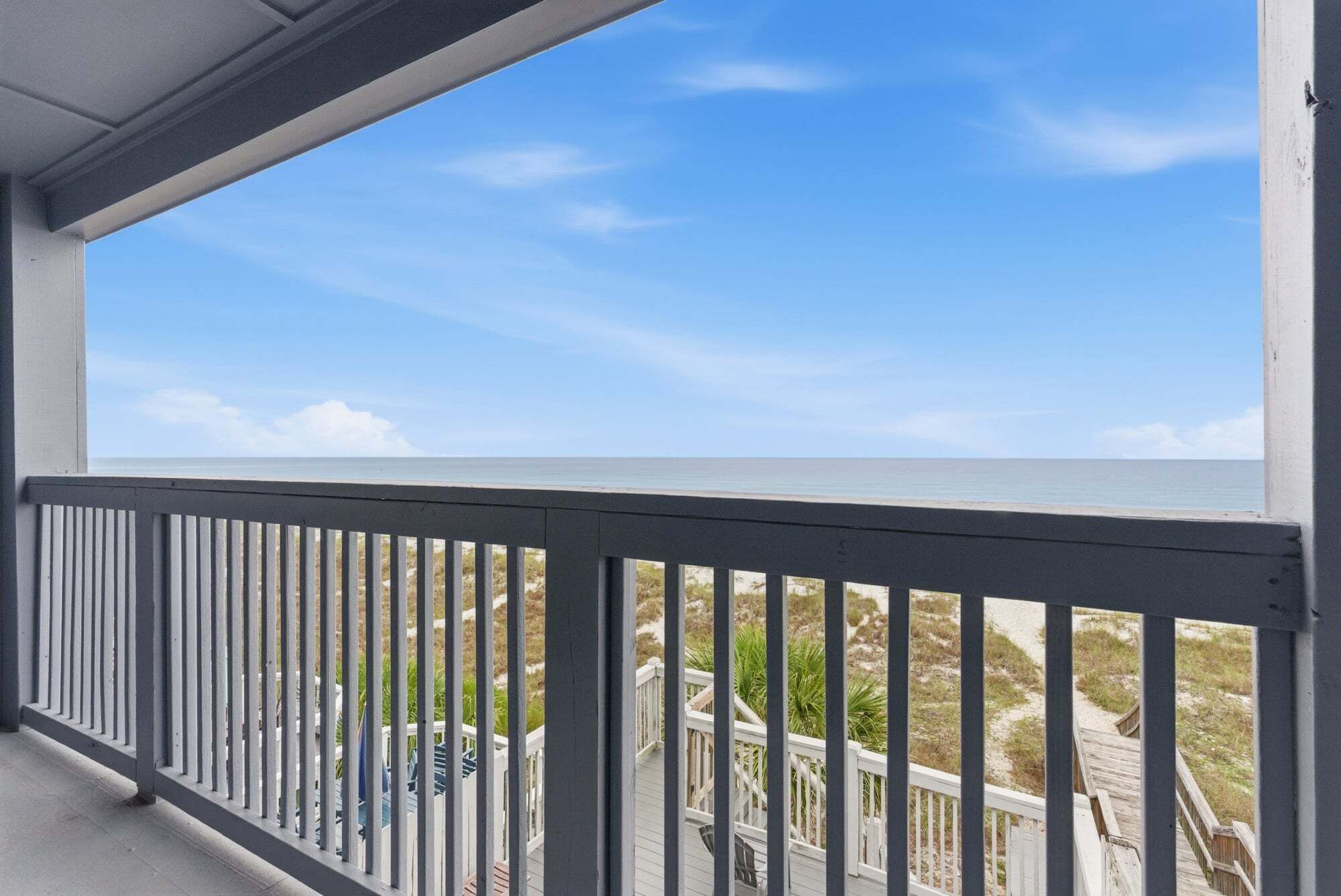 A balcony with a view of the beach and ocean.