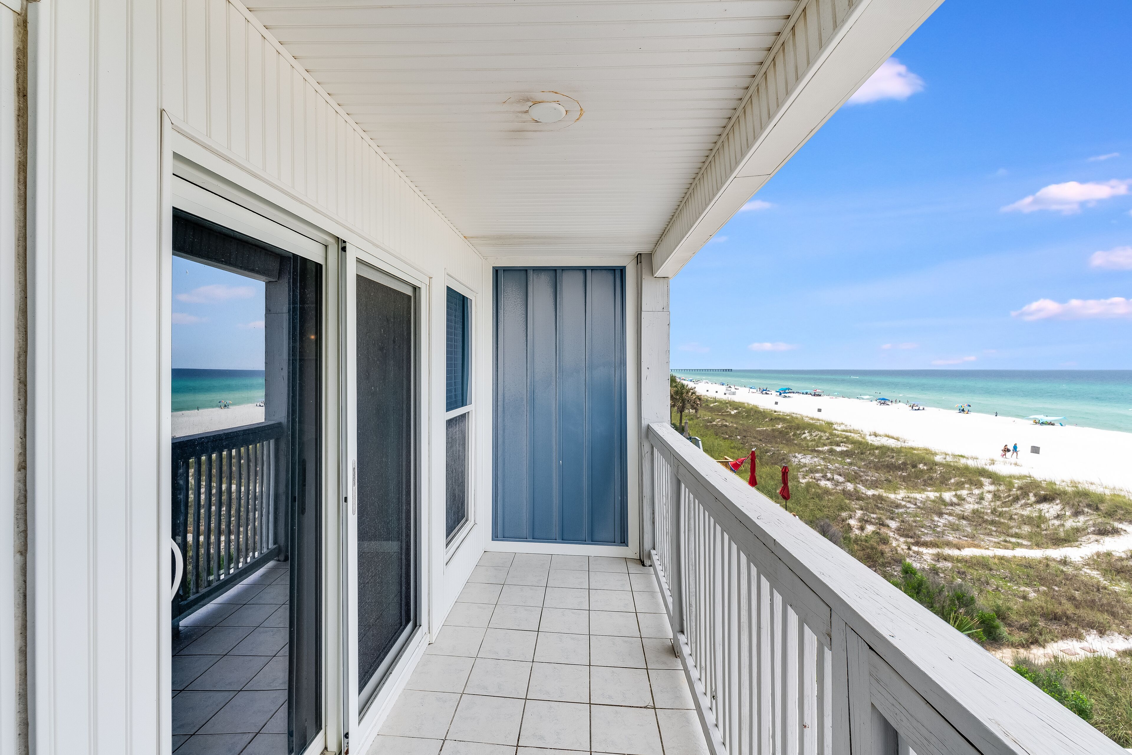 A balcony with a view of the beach and ocean.