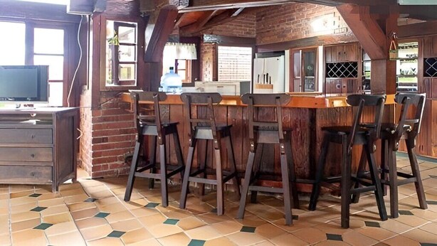 A rustic bar area with wooden stools and a brick wall backdrop. - Villa Lago Calima, a 5 min del Pueblo y Lago (Valle del Cauca)