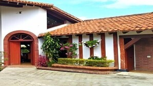 A two-story building with a brick facade, a large arched entrance, and a tiled roof. - Villa Lago Calima, a 5 min del Pueblo y Lago (Valle del Cauca)