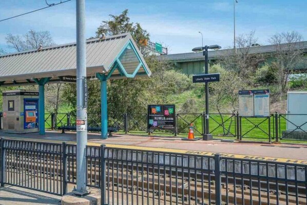 A train station platform with a shelter, a ticket machine, and a sign for Liberty State Park.