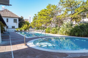 A pool area with a clear blue pool, lounge chairs, and surrounding greenery. - Summer Breeze Flat - St Augustine Green (Panama City Beach)