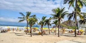 Une plage avec des palmiers, des parasols et des gens.