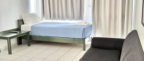 A modern hotel room with a bed, a sofa, and a small table.