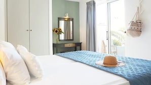 Ein Schlafzimmer mit einem Bett, einem Schminktisch, einem Spiegel und Blick ins Freie.